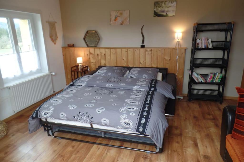 a bed in a bedroom with a wooden floor at Appartement Chez l'apiculteur in Travers