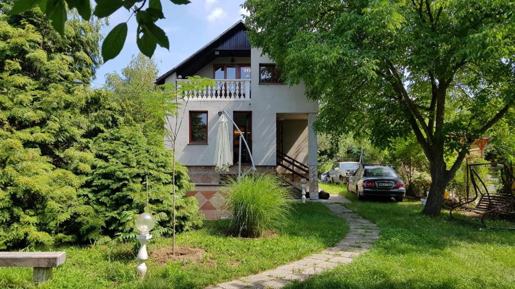 uma casa branca com um carro estacionado em frente dela em Hill View Holiday House nearby Budapest with AC & Pool em Pilisszentiván