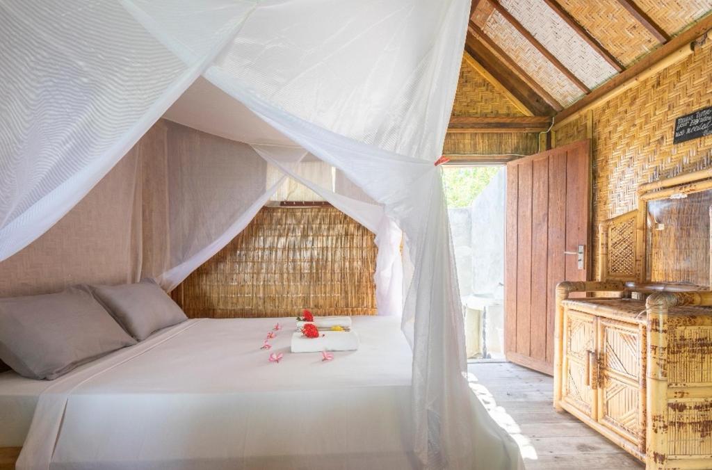 a bedroom with a white bed with a canopy at Abdi Fantastik in Gili Air