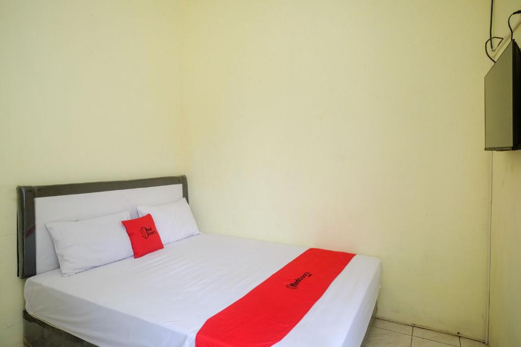 a white bed with a red blanket on it at RedDoorz Syariah near RS Permata Medika Ngaliyan Semarang in Tambakaji