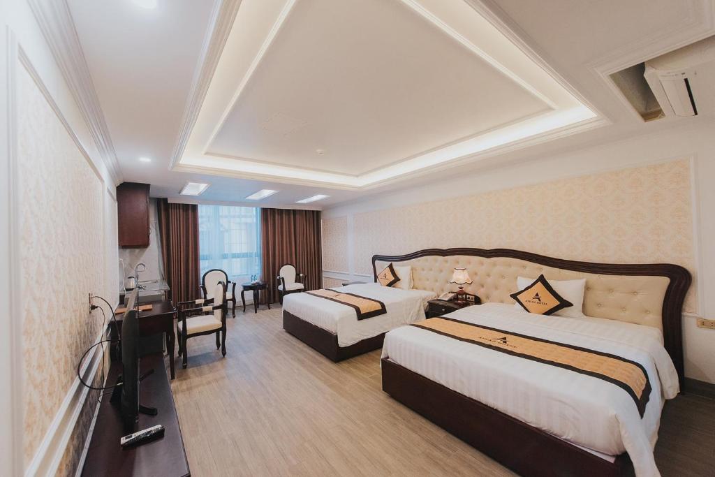 a hotel room with two beds and a desk at Asean Hotel in Hải Dương