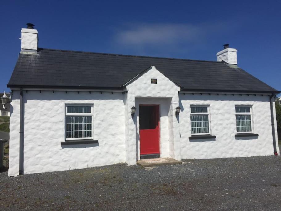 a small white house with a red door at Rose Cottage in Greencastle