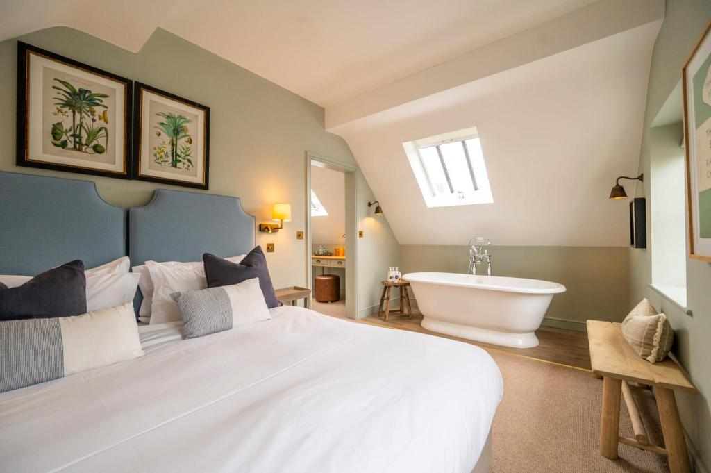 um quarto com uma grande cama branca e uma banheira em The Bottle & Glass Inn - Book All 3 Rooms em Henley on Thames