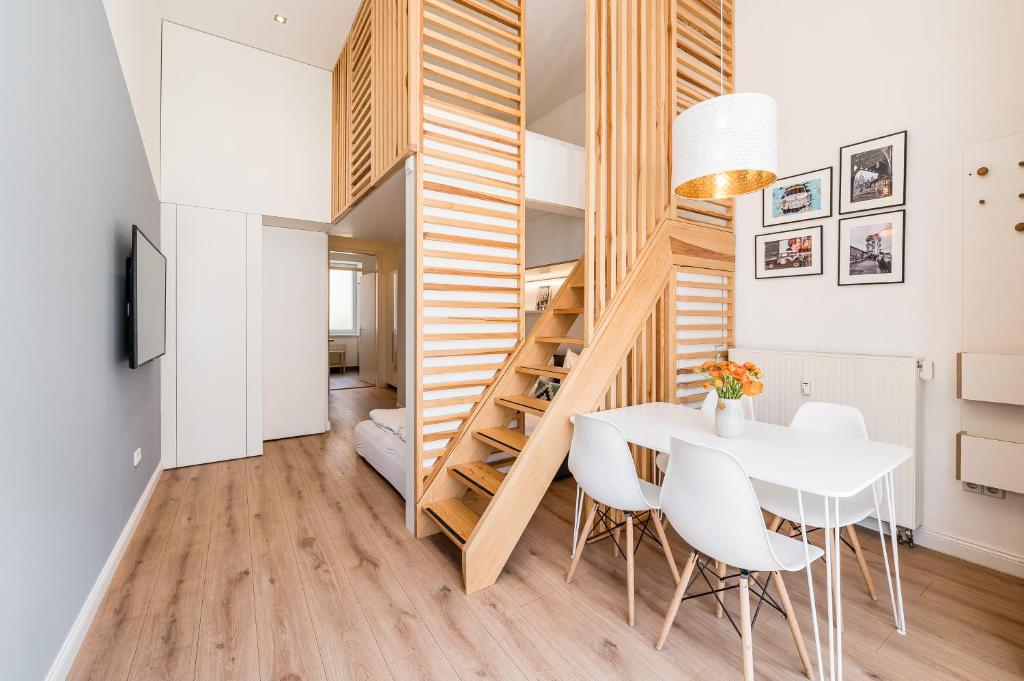 a small apartment with a staircase and a table and chairs at Stylish New Cube Loft by Berlin-Wall-Apartments in Berlin