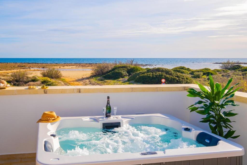 a bath tub with a bottle of wine in it next to the ocean at Villette Lux Fronte Spiaggia - Torre Pali in Torre Pali