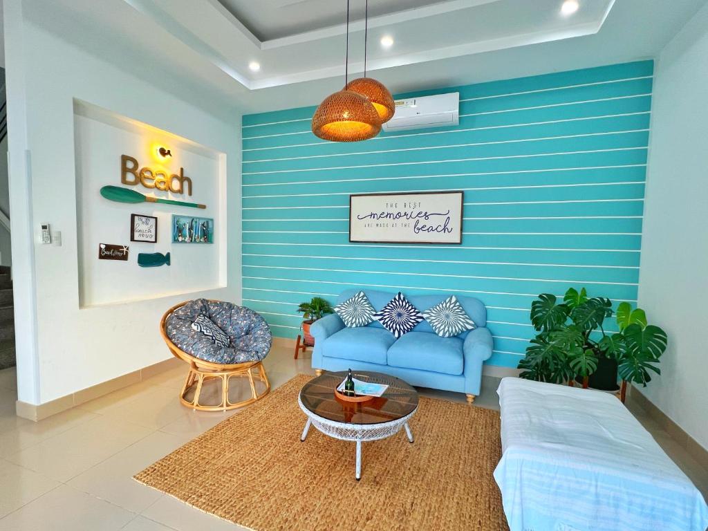 The Beachhouse Villa- 4 bedrooms Villa- 5' to Bai Sau Beach في Xã Thang Tam: غرفة معيشة مع جدران زرقاء وأريكة زرقاء