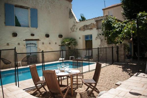 eine Terrasse mit einem Tisch und Stühlen neben einem Pool in der Unterkunft Maison Pelissier - Chambres d’hôtes avec piscine in Cuxac-dʼAude