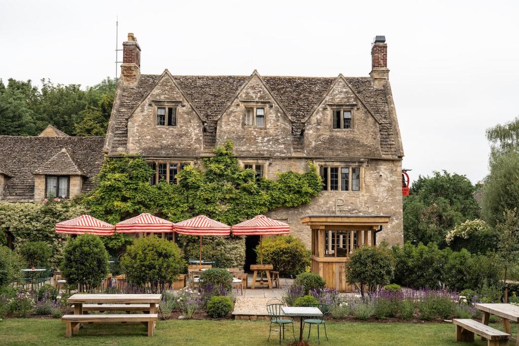 uma velha casa de pedra com mesas de piquenique em frente em The Double Red Duke, Cotswolds em Clanfield