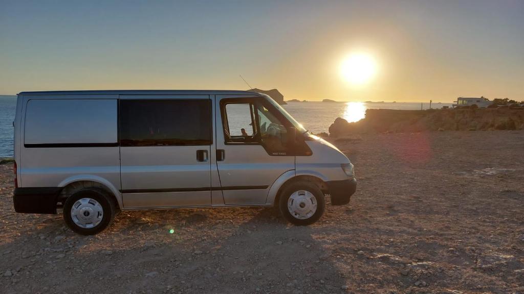 a white van parked on the beach with the sunset at Casa movil in Santa Gertrudis de Fruitera