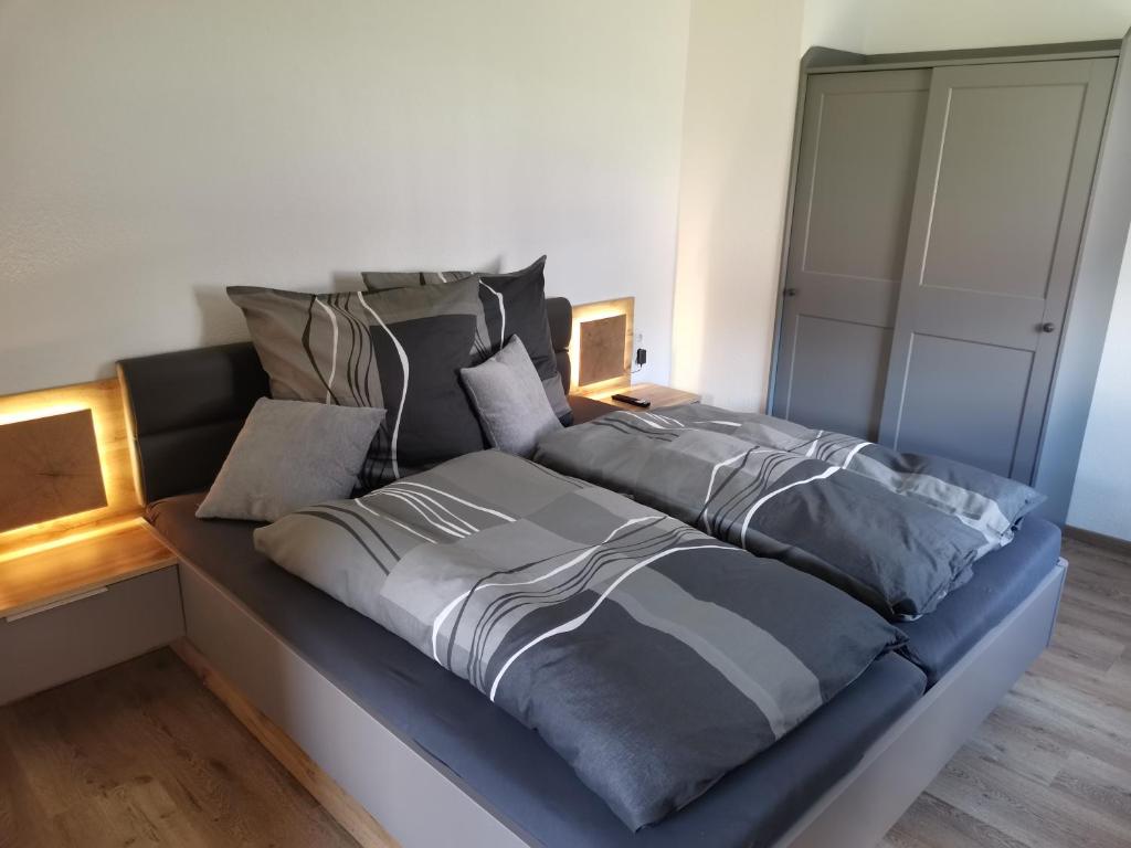 a bed with grey sheets and pillows on it at Ferienwohnung Paulinzella 9 inklusive Parkplatz und WLAN in Königsee