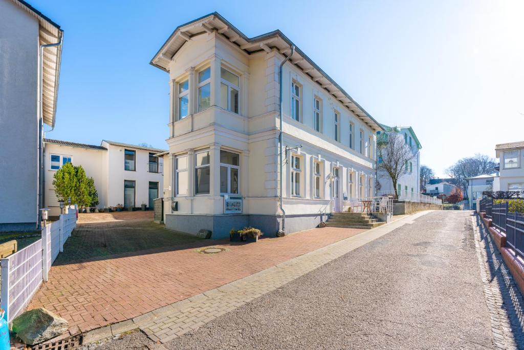 een groot wit huis in een bakstenen straat bij Pier 1 in Heringsdorf