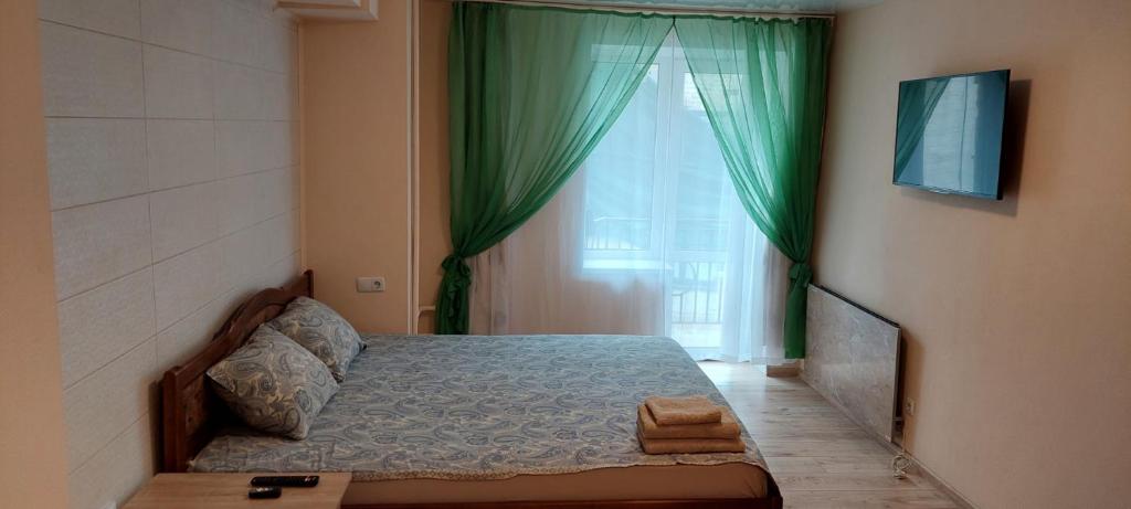 a bedroom with a bed and a window with green curtains at Harmony on Andrew descent in Kyiv