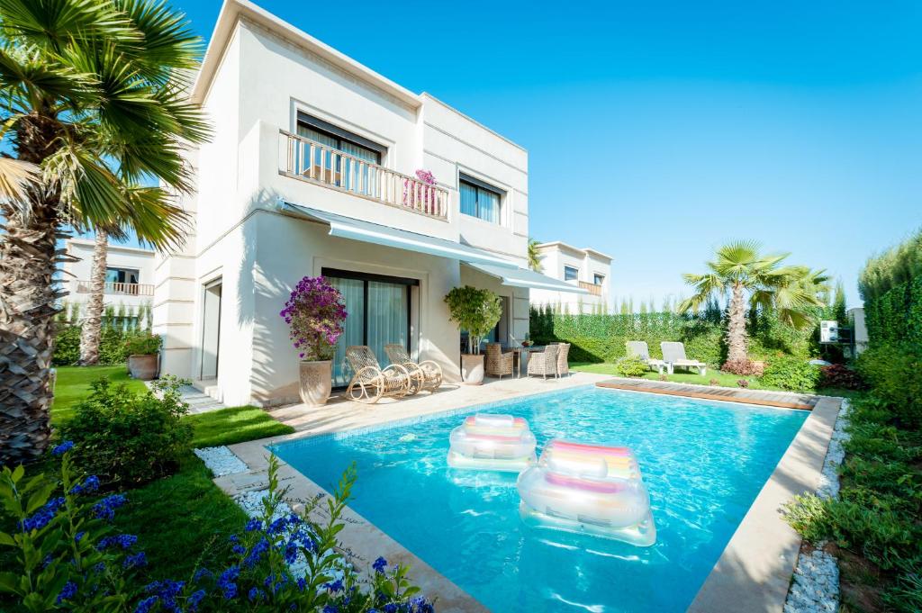 a villa with a swimming pool in front of a house at Villa Palmeraie Golf Agadir in Agadir