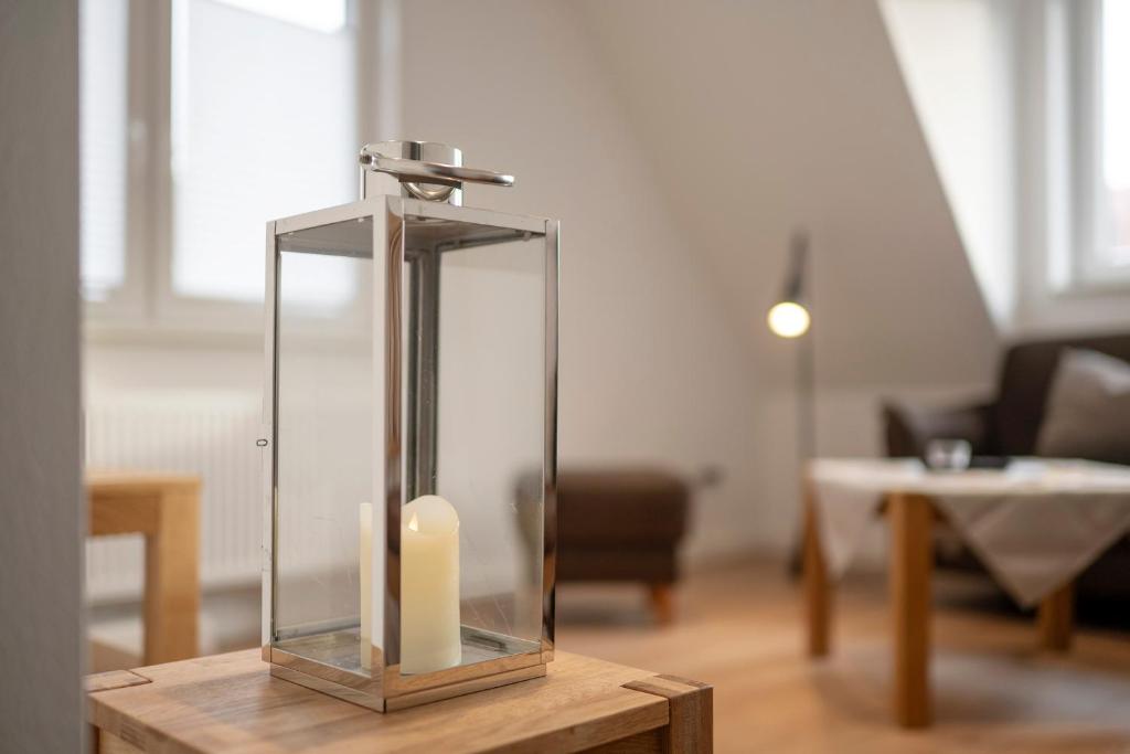 a candle in a glass case on a wooden table at Ferienwohnung '2' im OTTEN in Langeoog