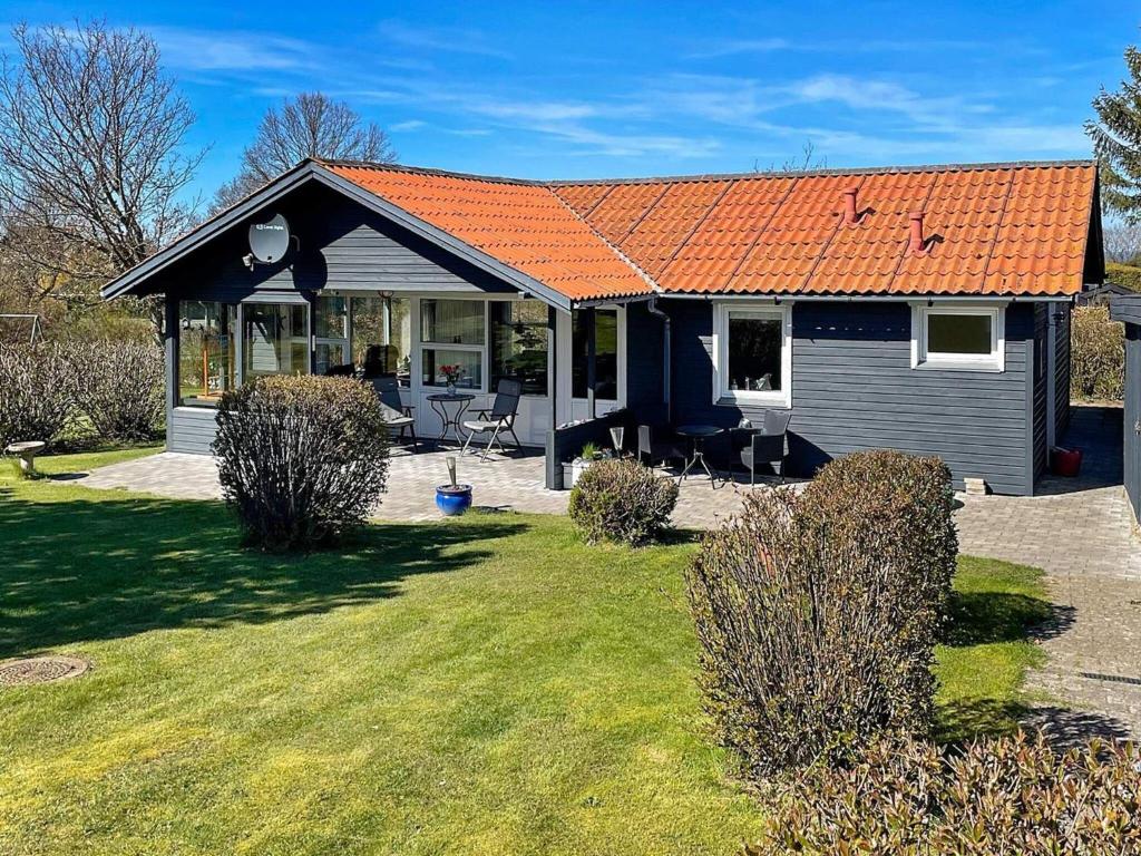 a small blue house with an orange roof at 6 person holiday home in Glesborg in Glesborg