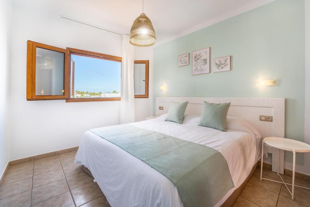 a white bedroom with a large bed and a window at Apartamentos Isla de Lobos - Adults Only in Puerto del Carmen