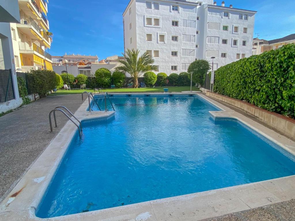 ein Schwimmbecken mit blauem Wasser vor einem Gebäude in der Unterkunft Oasis Sinia by Hello Homes Sitges in Sitges