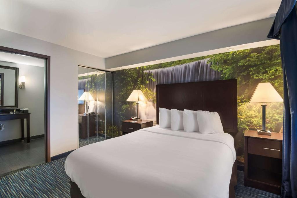 una camera d'albergo con un letto grande e una grande finestra di Clarion Pointe Downtown a Syracuse