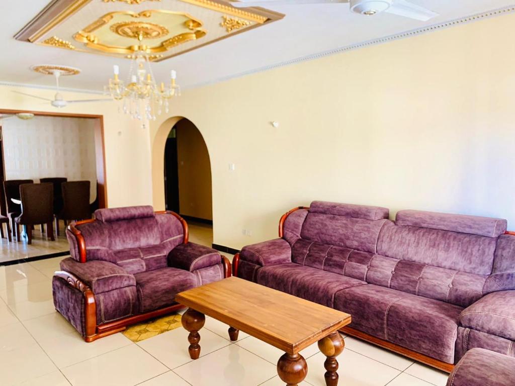 un soggiorno con divano e 2 sedie di Lux Suites Furaha Holiday Apartments Nyali a Mombasa