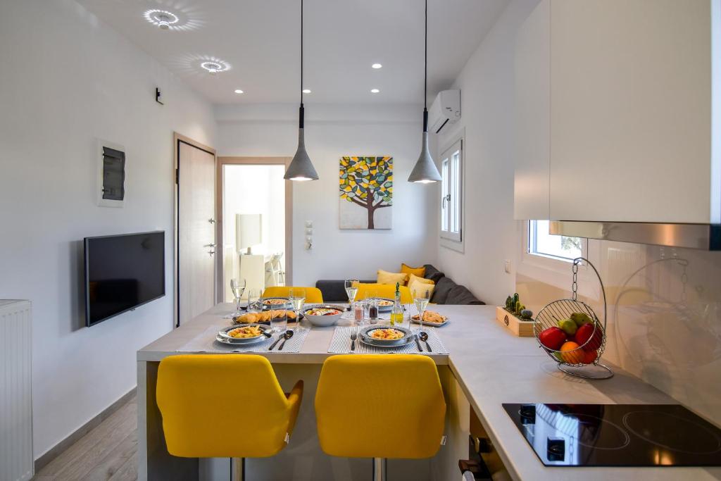 a kitchen and dining room with a table and yellow chairs at White Rock Milos Suites in Adamantas