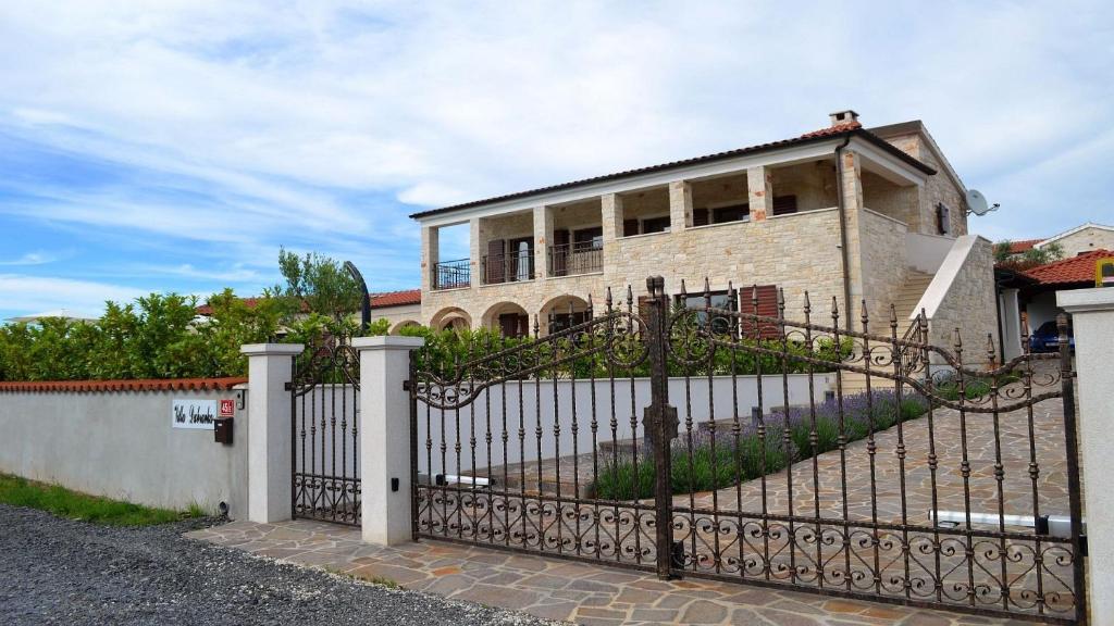 a house with a wrought iron fence in front of it at Spacious poolside villa with beautiful garden in Kringa in Pinezići