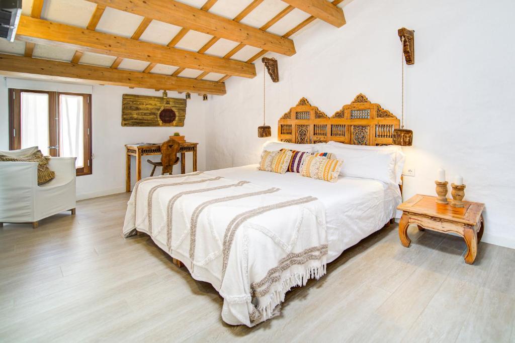 a bedroom with a large white bed and a table at Calma Hotel in Ciutadella
