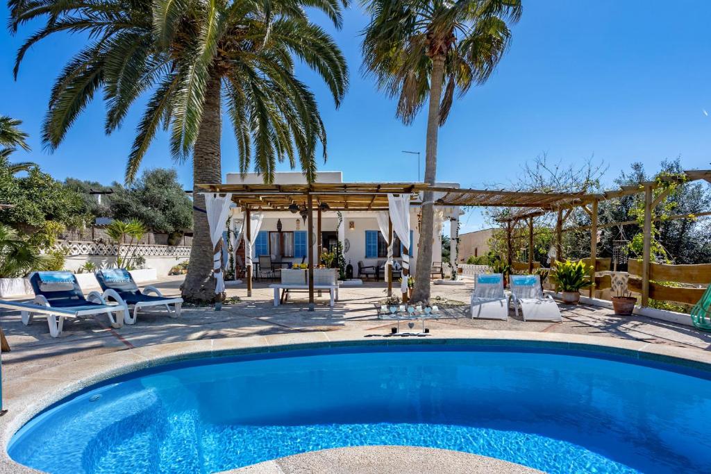 a swimming pool with a gazebo and palm trees at Cas Padri by dracmallorca in Santanyi