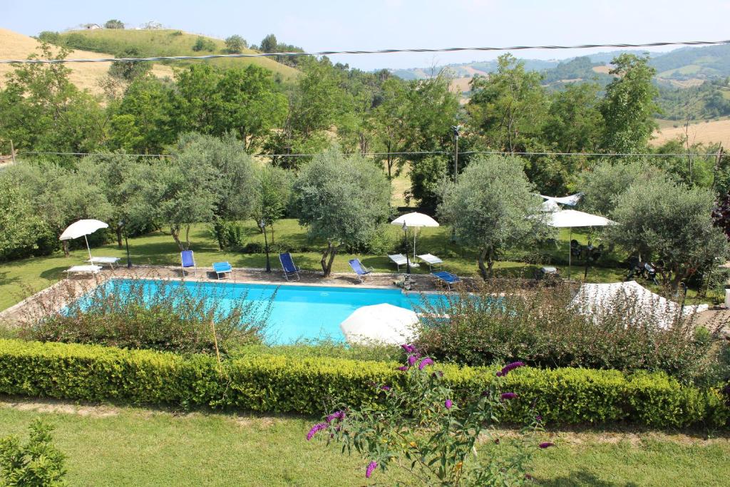 una piscina en un jardín con sombrillas en Agriturismo La Solagna, en Montebello di Bertona