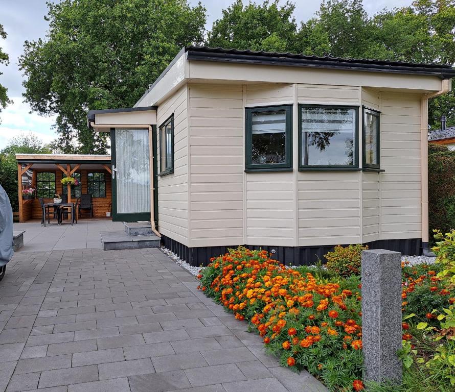a tiny house with a patio and flowers at Chalet Zeeweg in Nunspeet