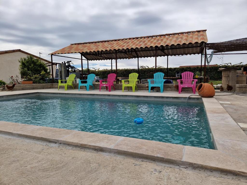 - un groupe de chaises colorées assises autour d'une piscine dans l'établissement Mazet d El gato, à Arles