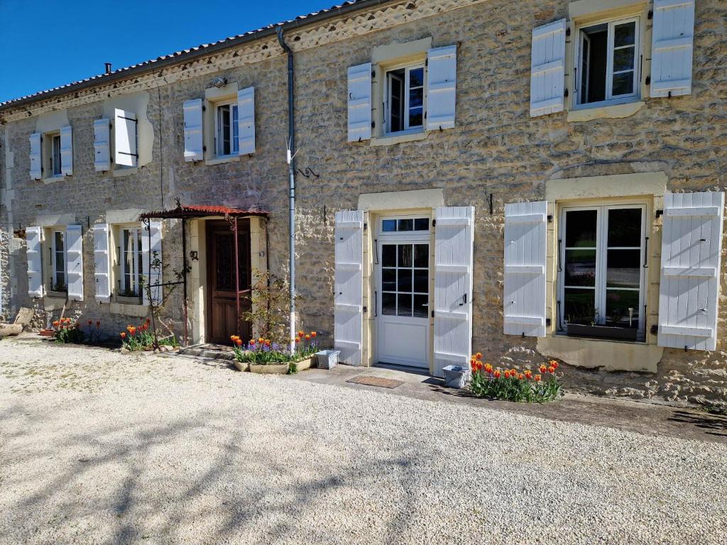 a stone house with white doors and flowers in front of it at ESCALE AU CLOS SAINT MARTIN DE JUILLERS Gîtes et Chambres d'hôtes in Saint-Martin-de-Juillers