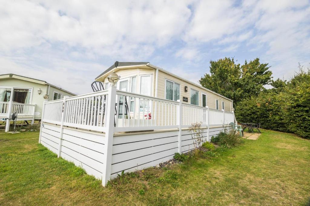 a house with a white fence in a yard at Beautiful 8 Berth Caravan At Cherry Tree Holiday Park In Norfolk Ref 70803c in Great Yarmouth