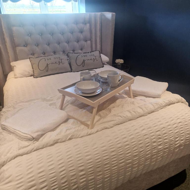 ein Bett mit einem Tisch mit Tassen und Untertassen darauf in der Unterkunft Lenox Bed and Breakfast in Hale