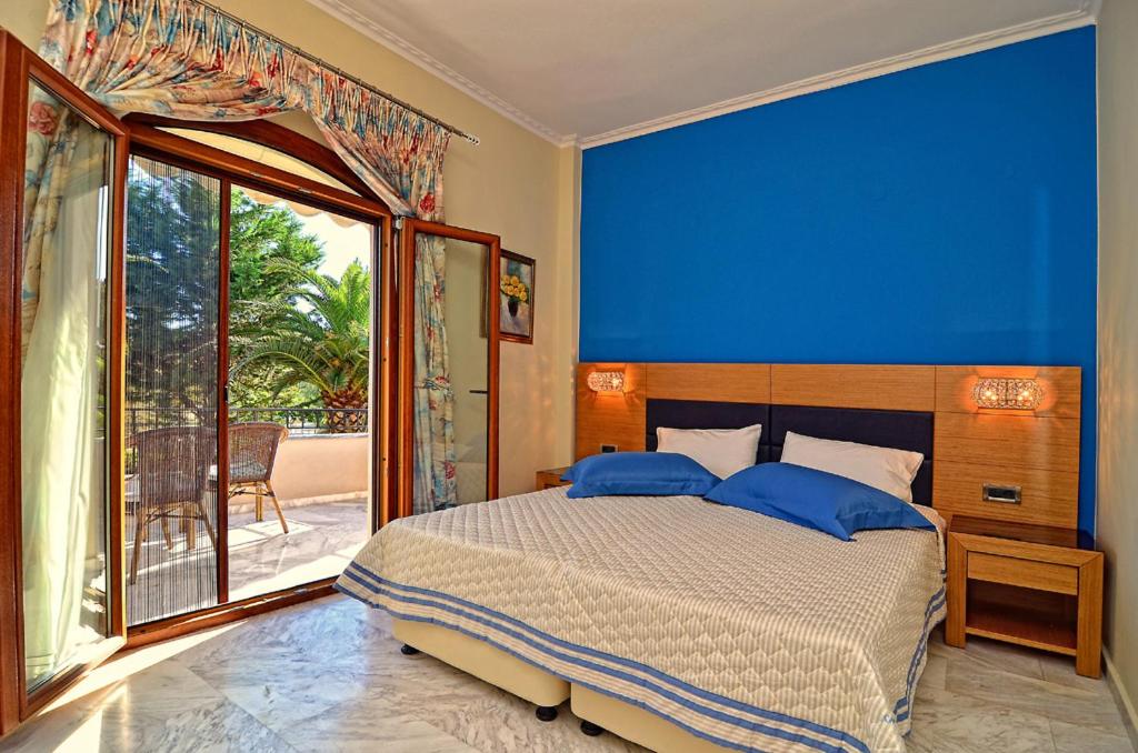 sypialnia z dużym łóżkiem z niebieską ścianą w obiekcie Villa Ilias w mieście Parga