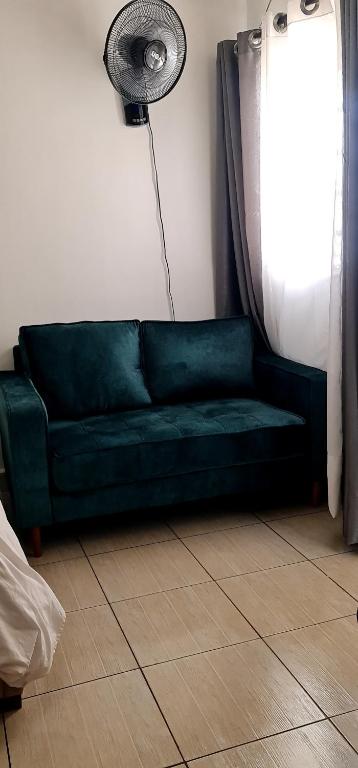 a green couch in a living room with a fan at Eagles nest III Furnished apartments in Nairobi