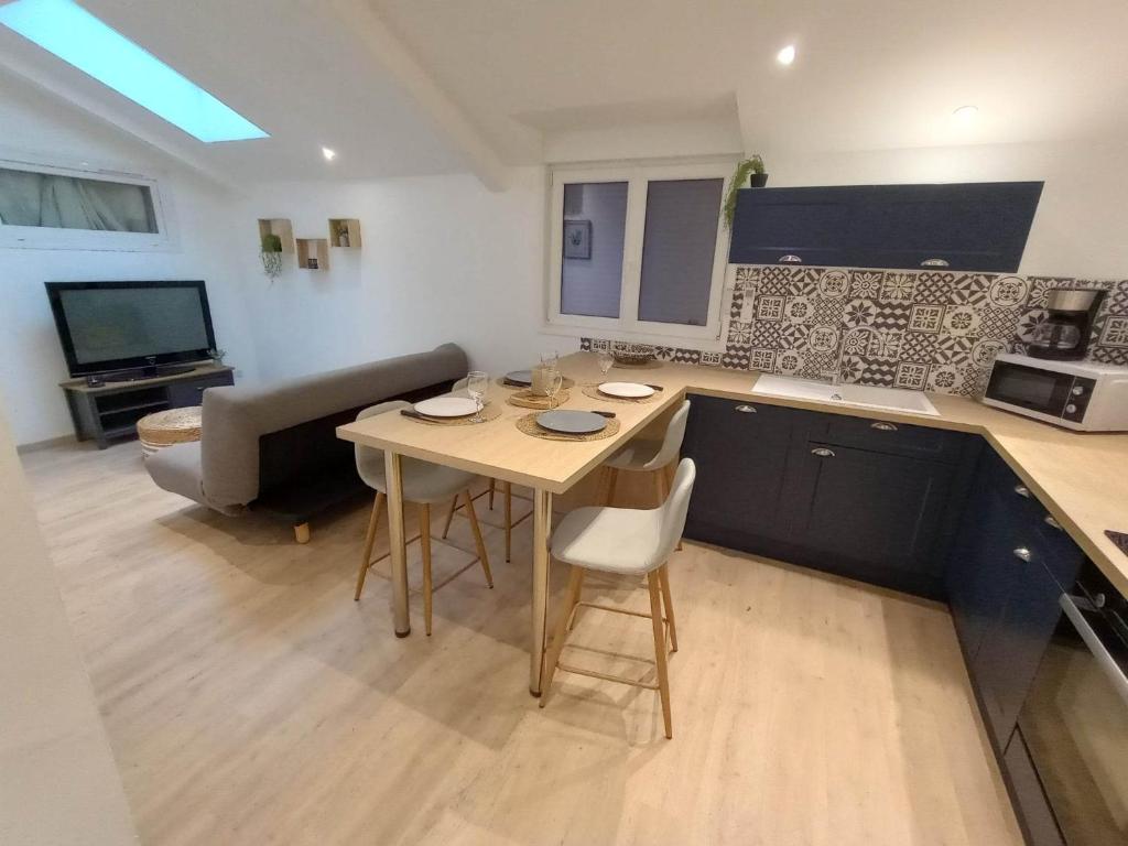 a small kitchen with a table and a couch at Cottage neuf - Forêt de Tronçais in Urçay