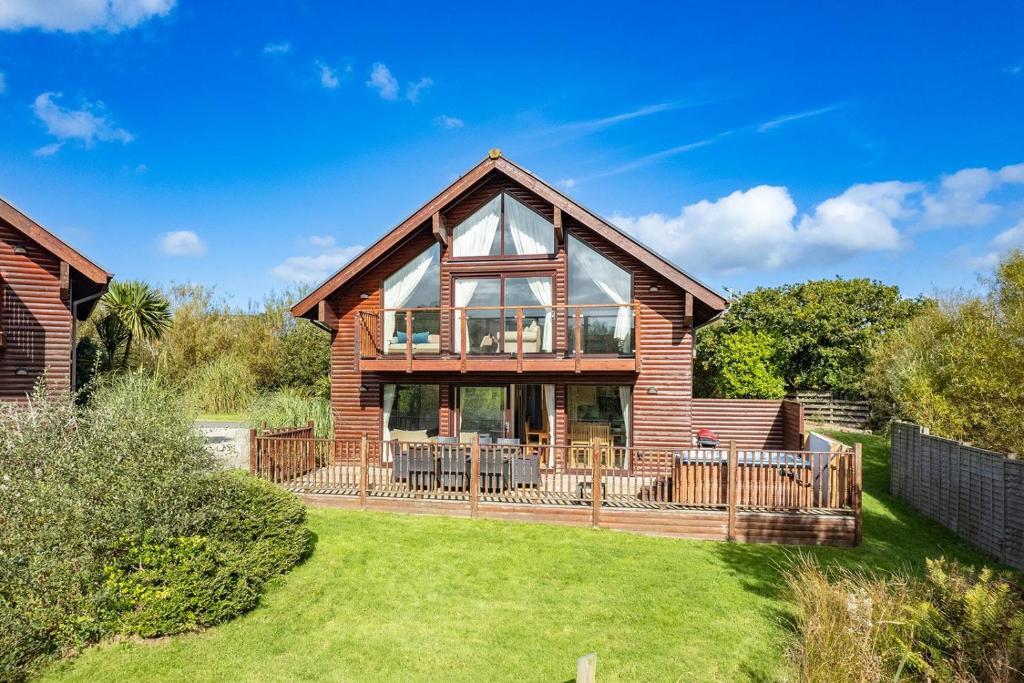 a log home with a large deck on a lawn at Skylark sleeps 8 private Hot Tub & Dogs welcome Nr Padstow, Resort Pool Bar & Watersports in Saint Columb Major