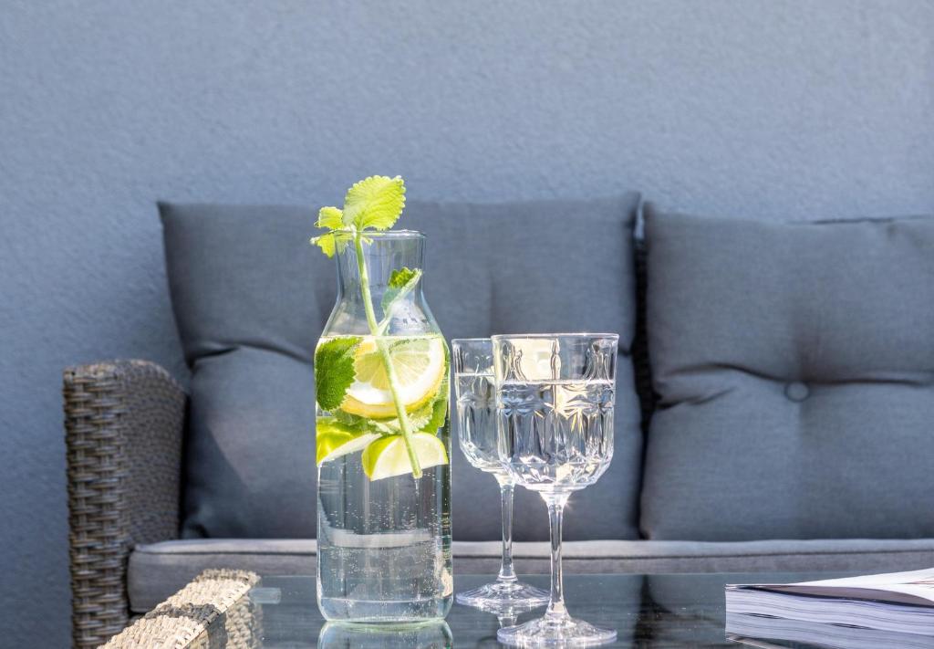 un vaso di vetro con una pianta accanto a due bicchieri. di GENIO 7 apartamentai a Palanga