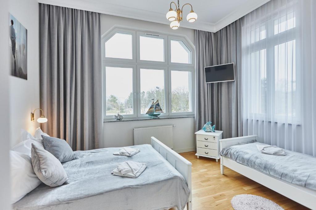 a white bedroom with two beds and a window at WISUS 24 in Świnoujście
