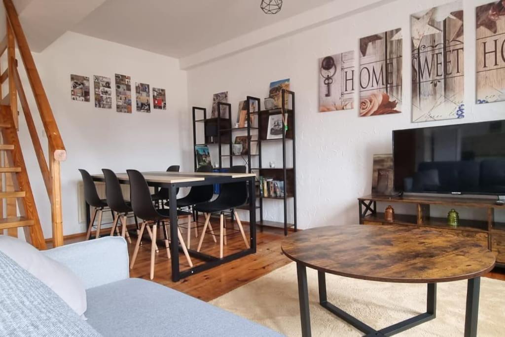 a living room with a table and a tv at Cosy Triplex 3 chambres in Pont-de-lʼArche