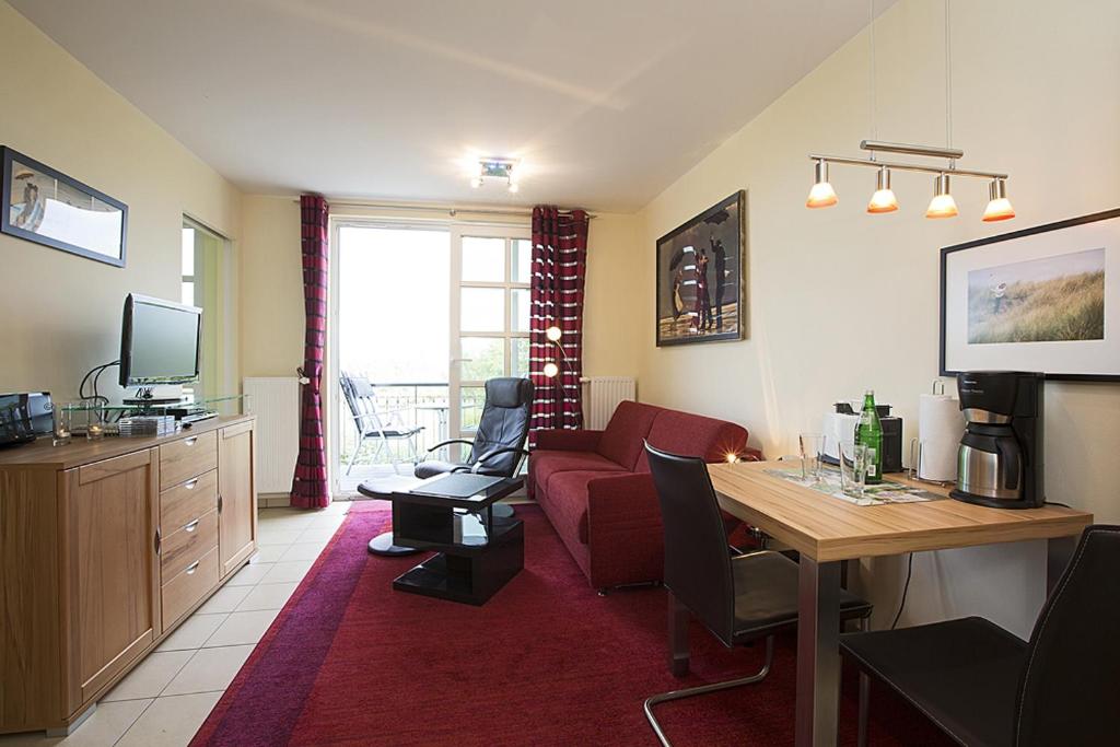 ein Wohnzimmer mit einem roten Sofa und einem Tisch in der Unterkunft Residenz am Balmer See - BS 51 mit Wellnessbereich in Balm