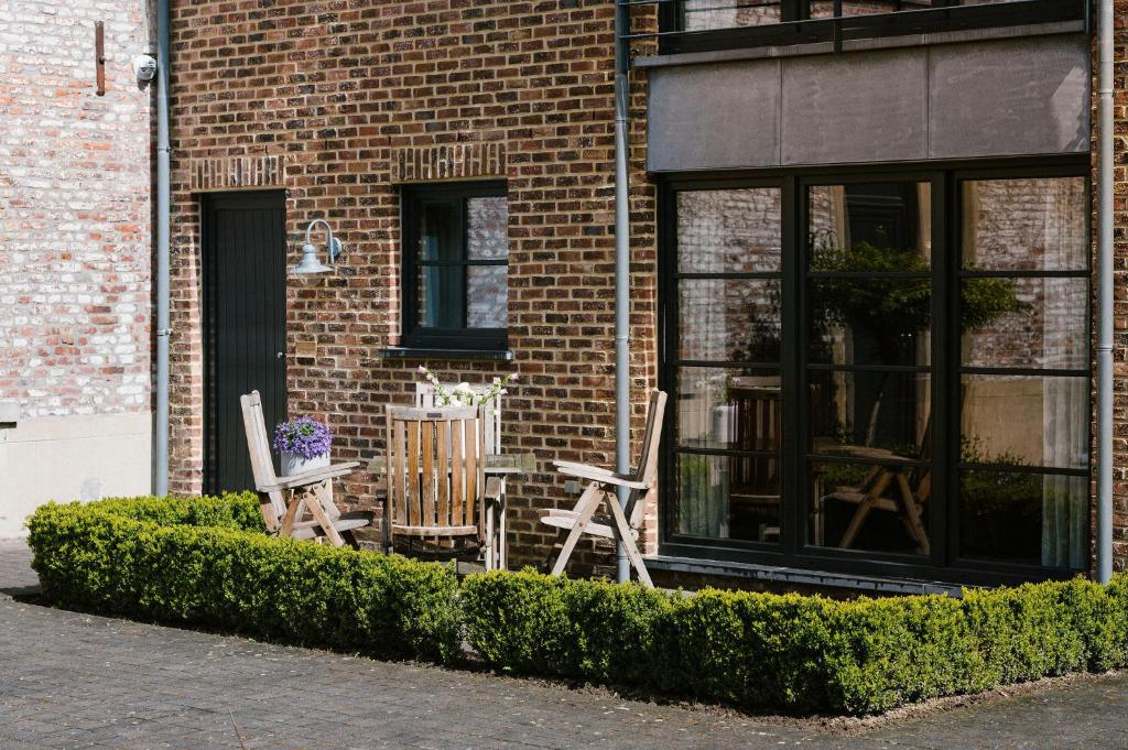 2 chaises et une table devant un bâtiment en briques dans l'établissement Hoeve de Reetjens - La Porcherie, à Bilzen