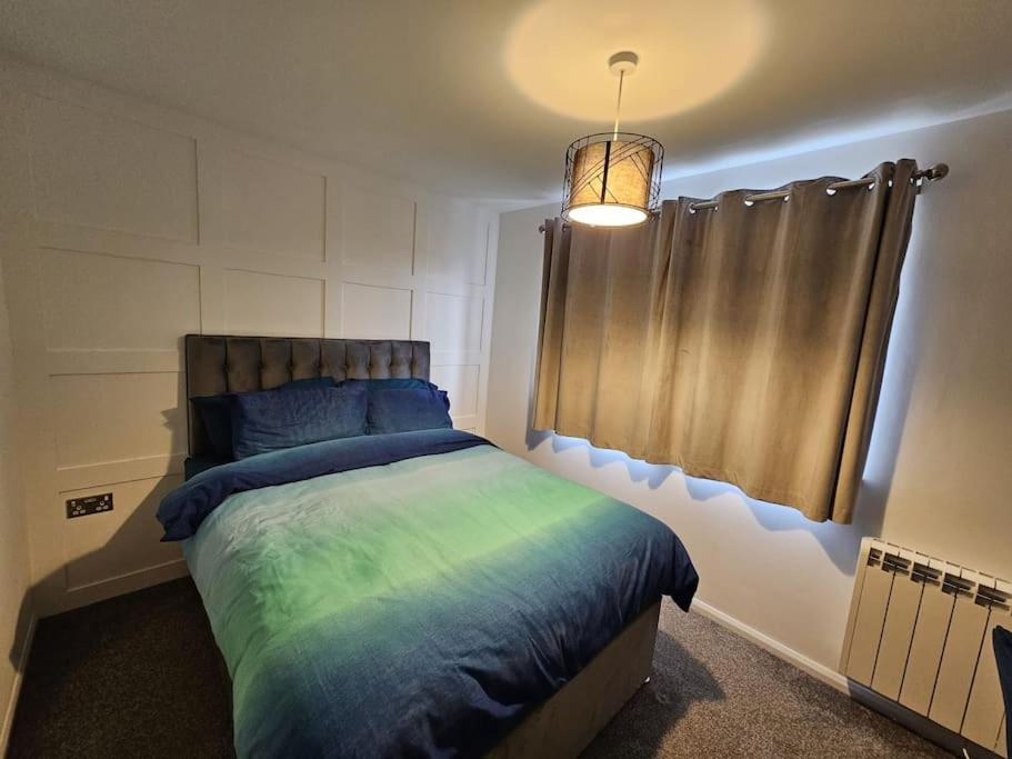 a bedroom with a bed with blue and green sheets at Entire Spacious Modern One Bedroom House in Swindon