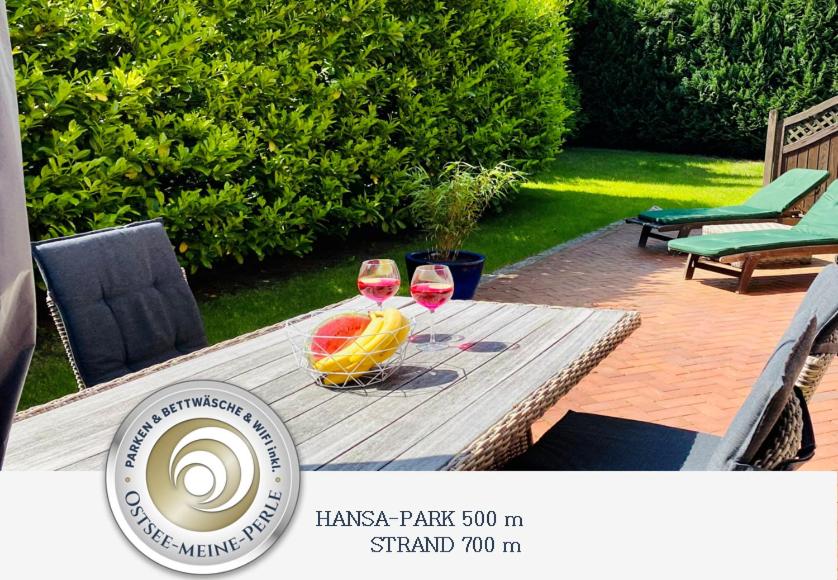 a table with two glasses of wine and a bowl of fruit at FeWo SONNENDECK Familien-strandnah-Garten-Hunde-Sport-und Schwimmbadnah-HansaPark in Sierksdorf