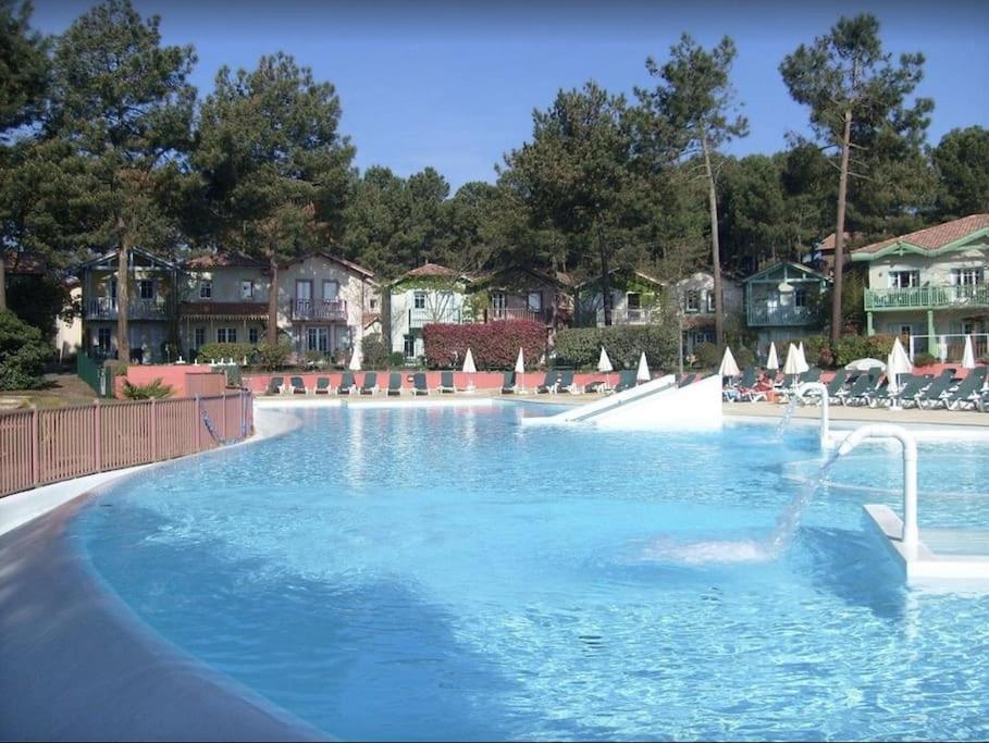 duży basen z błękitną wodą w ośrodku wypoczynkowym w obiekcie Maison NAUCALA proche de la piscine w mieście Lacanau