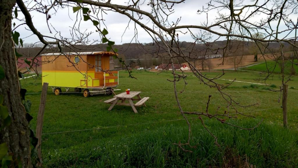 ein kleines Haus und ein Picknicktisch auf einem Feld in der Unterkunft Véritable roulotte à la campagne in Bassillon-Vauzé