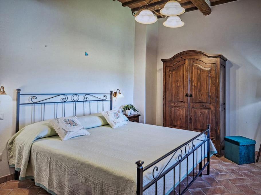 ein Schlafzimmer mit einem großen Bett und einer Holztür in der Unterkunft Dimora del Grillo in Montepulciano