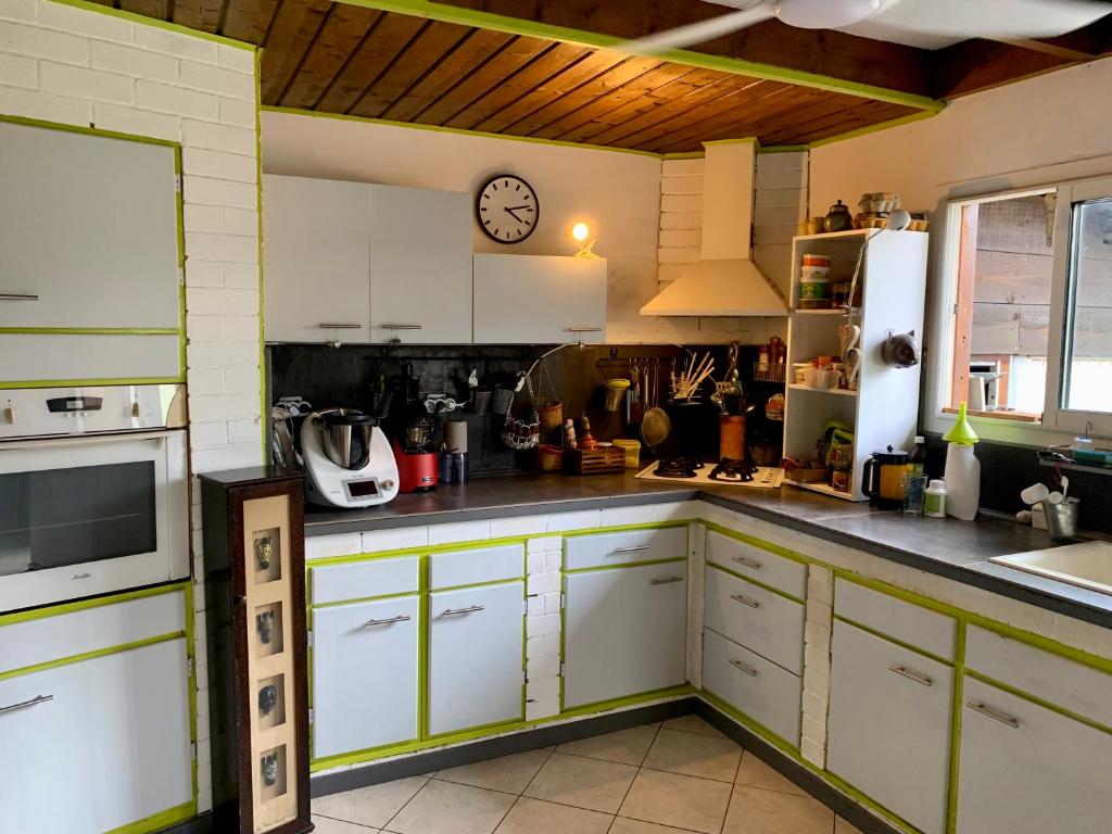 a kitchen with white cabinets and a clock on the wall at Le Dodo Salé in Étang-Salé