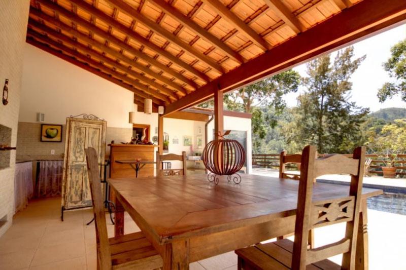 uma sala de jantar com uma mesa de madeira e uma grande janela em Pousada Alto Itaipava em Itaipava