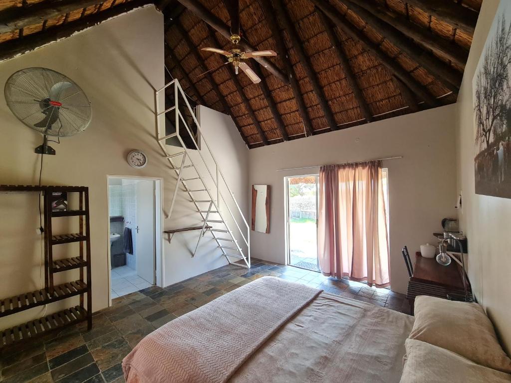1 dormitorio con 1 cama y ventilador de techo en Tamboti Farm Accommodation, en Tsumeb